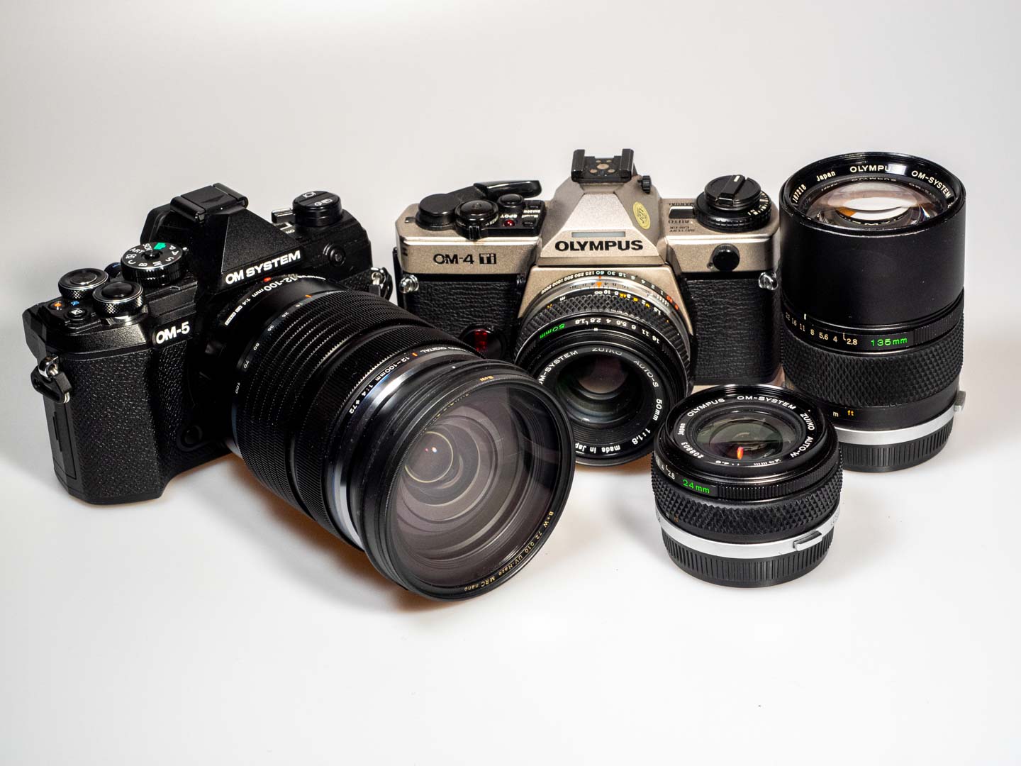 Produktfoto zeigt OM System OM-5 DSLM und Olympus OM-4 Ti, jeweils mit Objektiven